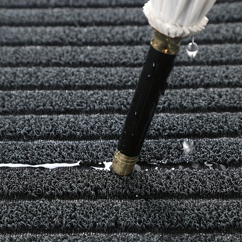Close-up of a black garden hose with brass fitting on a textured surface.