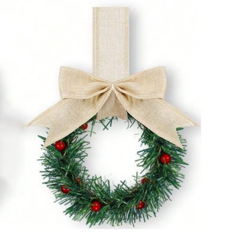 Small green wreath with red berries and a beige bow on a white background