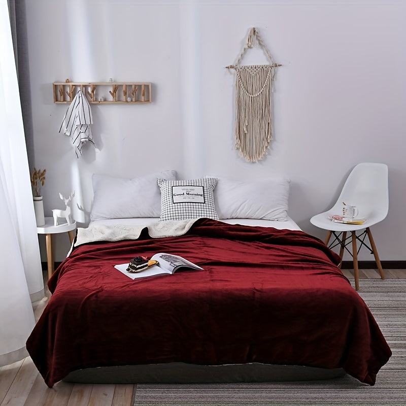 Bedroom with a bed covered in a red blanket, pillows, and a magazine.