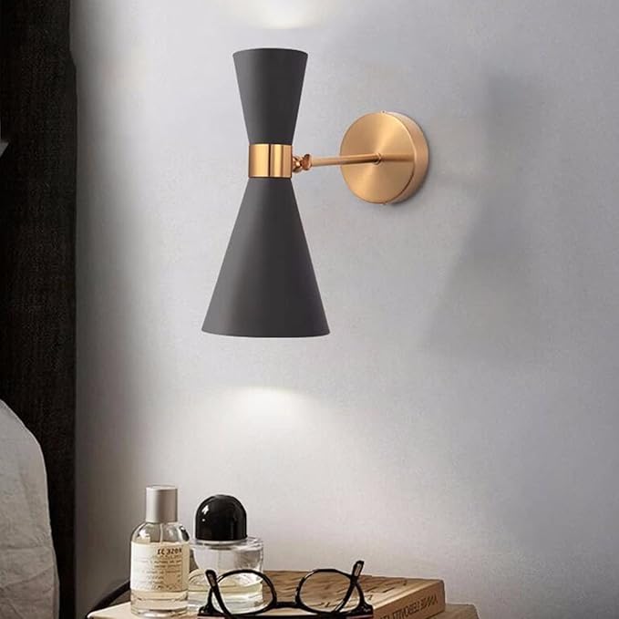 Modern wall sconce with black shade and gold fixture on a gray wall.