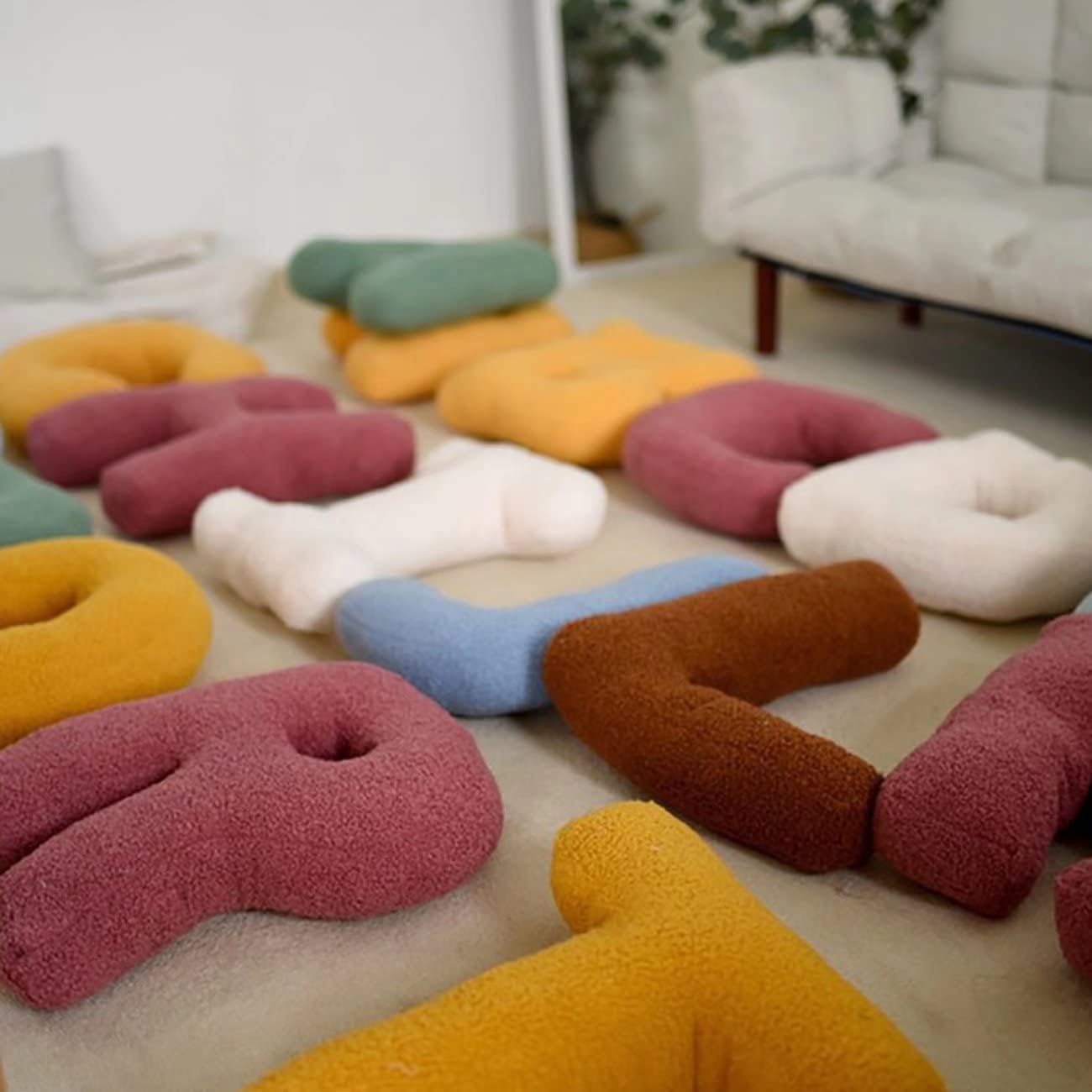 Colorful donut-shaped cushions on a wooden floor with a blurred indoor background.