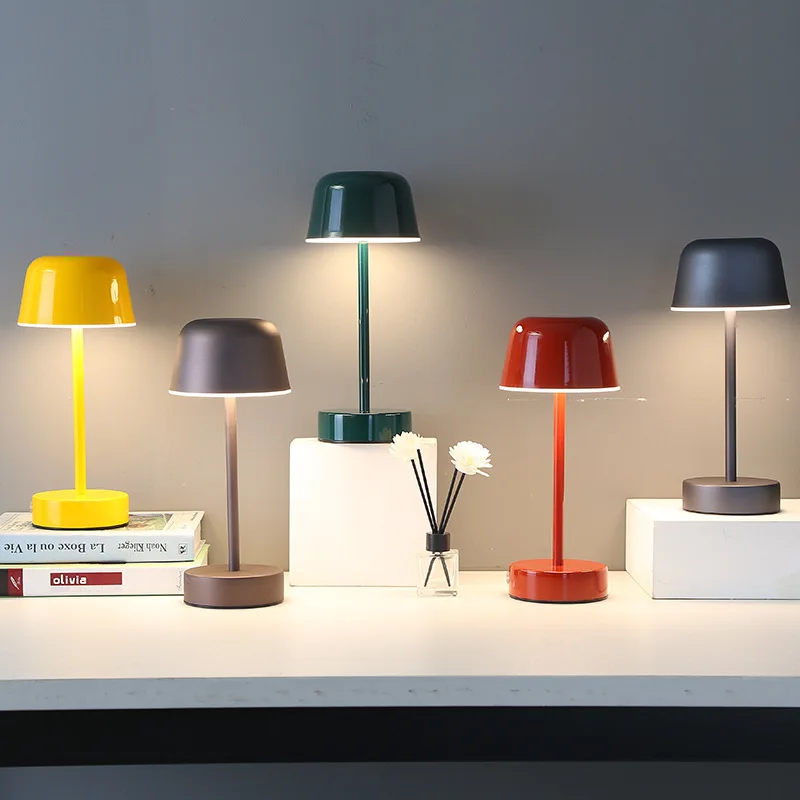 Five colorful table lamps on a surface with a neutral background