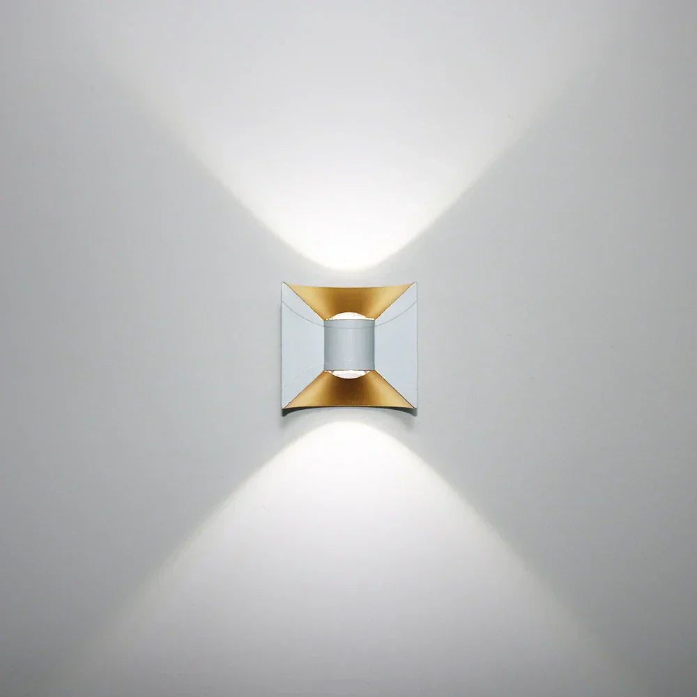Modern wall light fixture with gold and silver design on a gray background