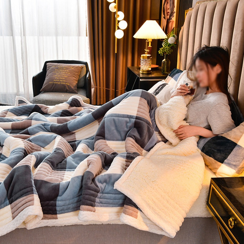 Woman sitting on a bed with a checkered blanket in a cozy bedroom.