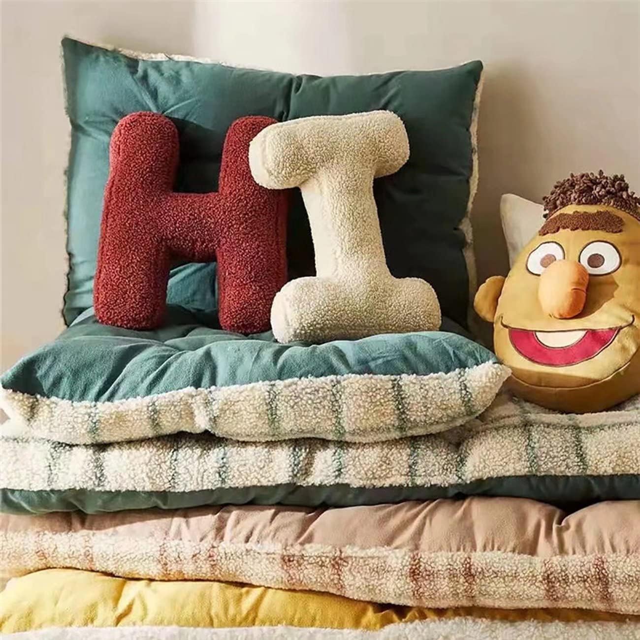 Stack of colorful pillows with a character pillow on a bed