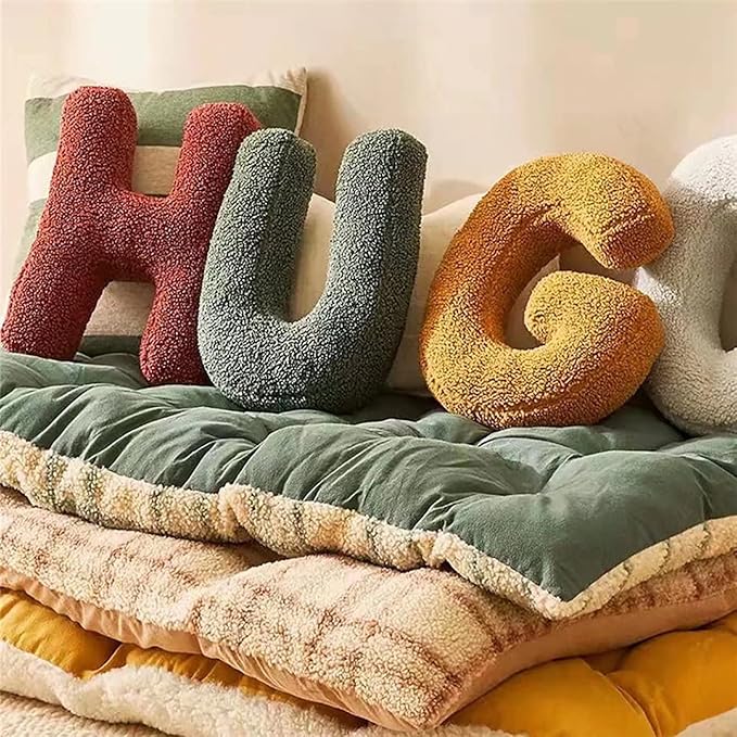 Letter-shaped cushions spelling 'HUG' on a soft surface with a blanket.