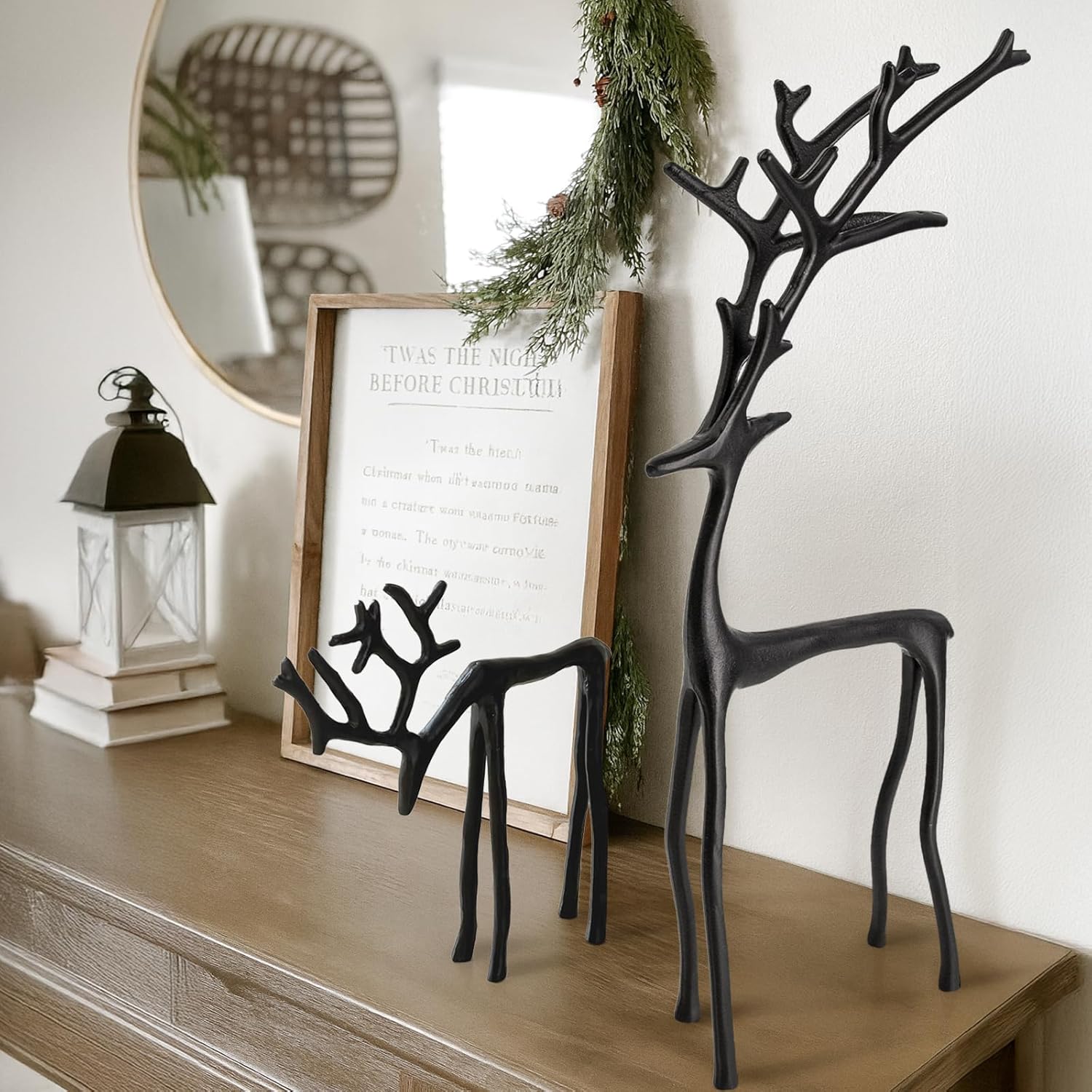 Decorative black deer statues on a wooden surface with a framed sign and lantern in the background.