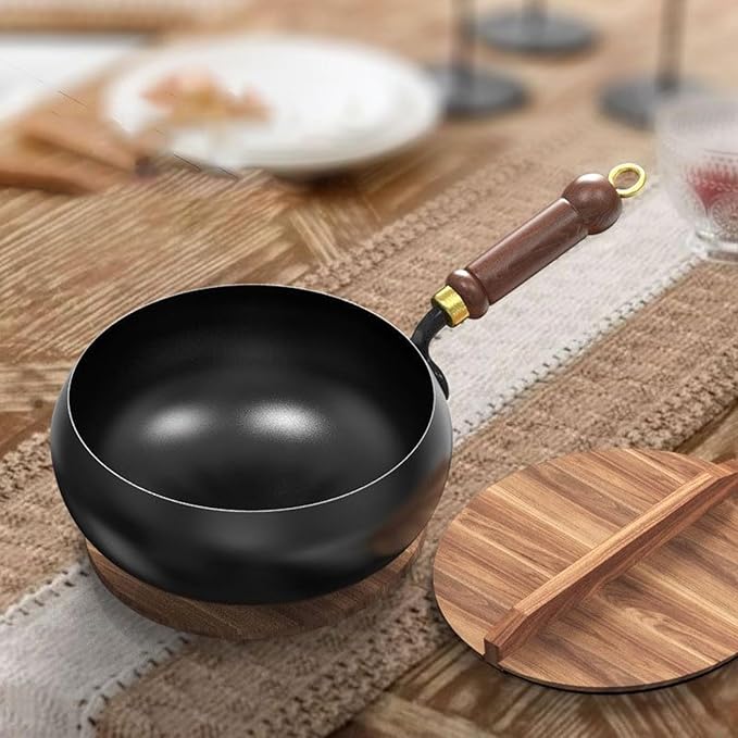 Black frying pan with wooden handle on a wooden table