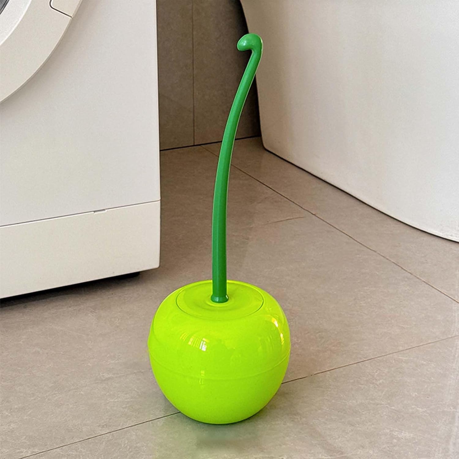Green and yellow toilet brush on a tiled bathroom floor.