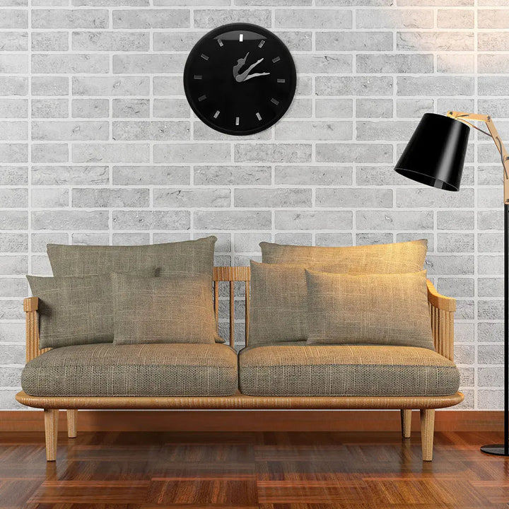 Sofa with cushions against a brick wall with a clock, lamp, and wooden floor.