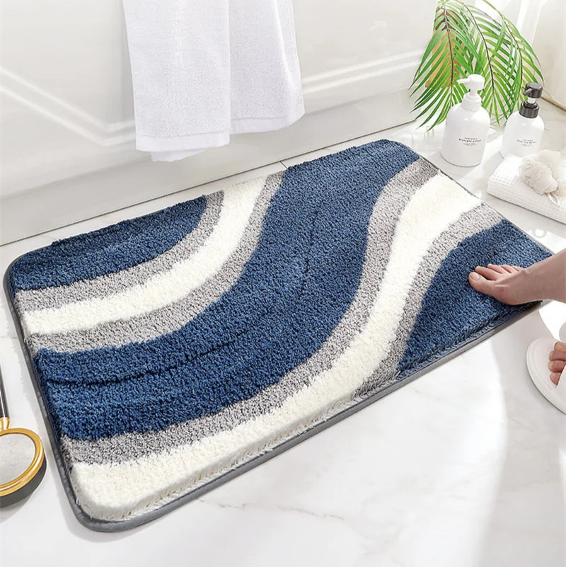 Bathroom mat with blue and gray wavy pattern on a white floor