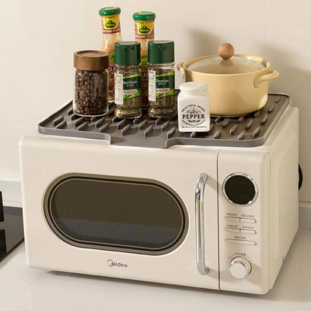 White microwave with a spice rack on top containing various jars and a pot.