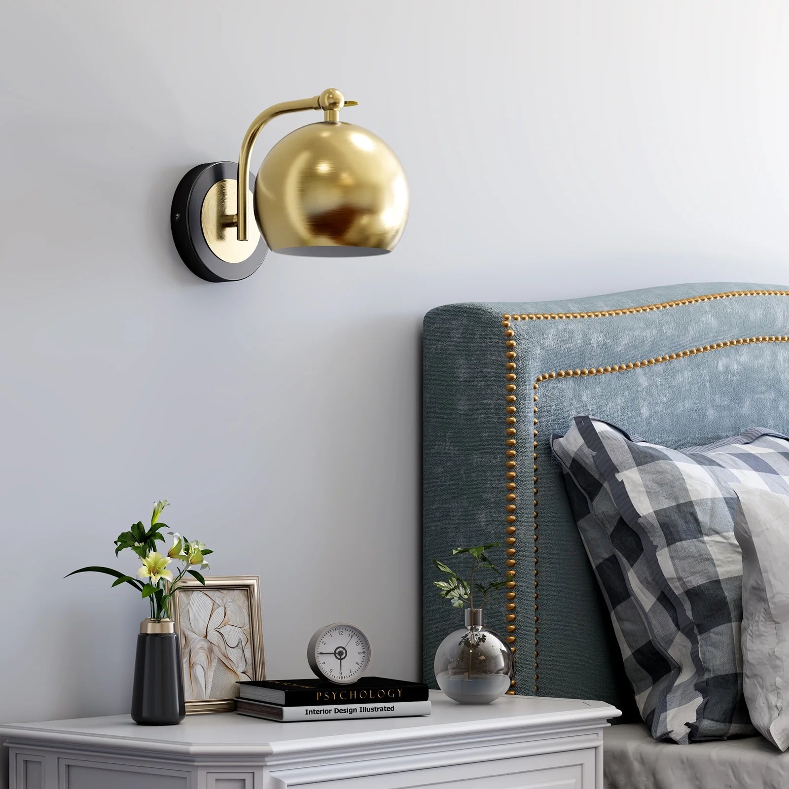 Gold wall sconce above a nightstand with decorative items in a bedroom setting.