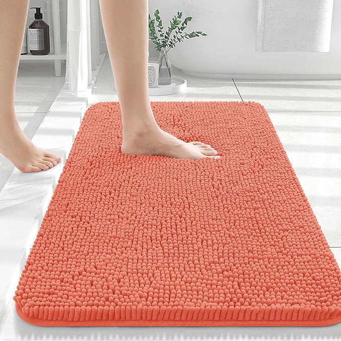 Person stepping onto a coral bath mat in a bathroom setting.