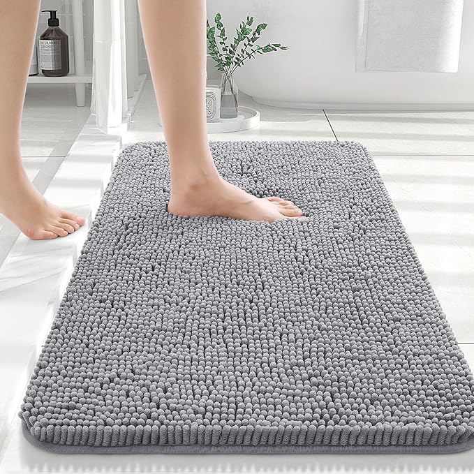 Gray bath mat on a bathroom floor with a person stepping onto it.
