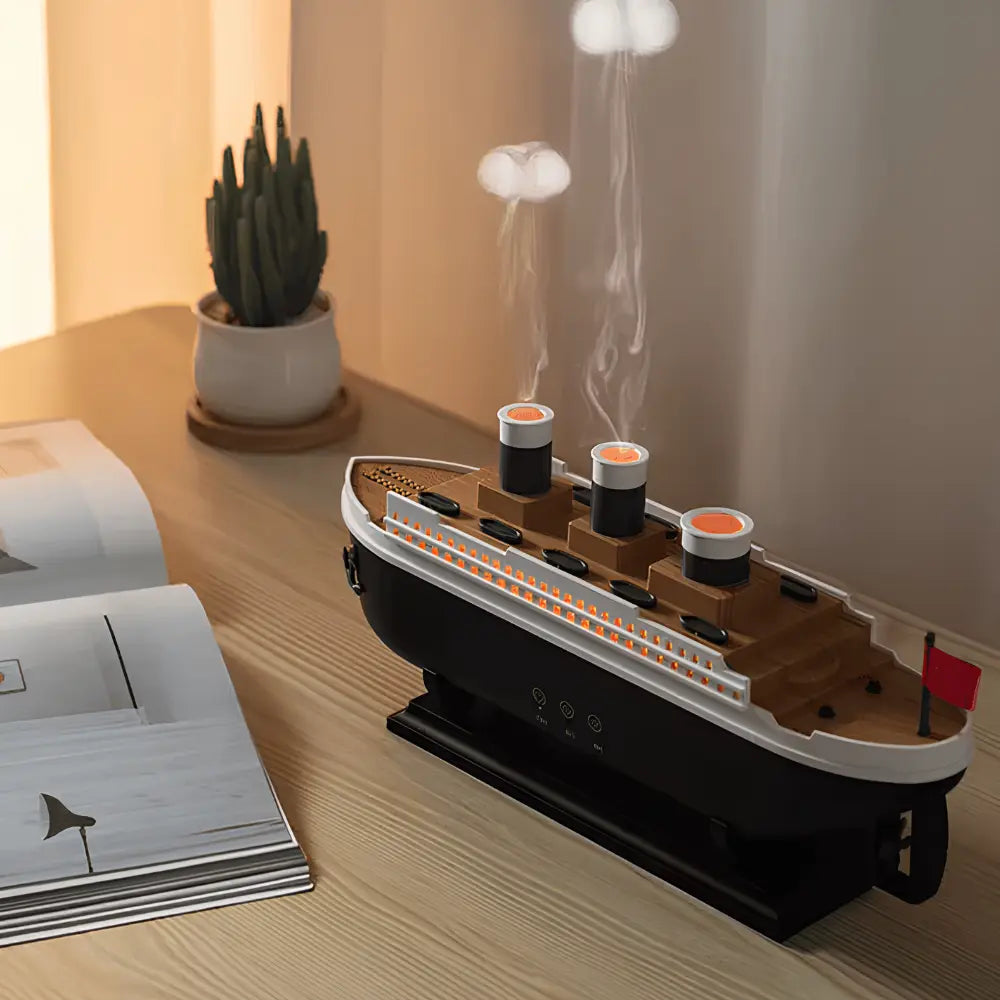 Model of a ship on a wooden surface with a lamp and plant in the background