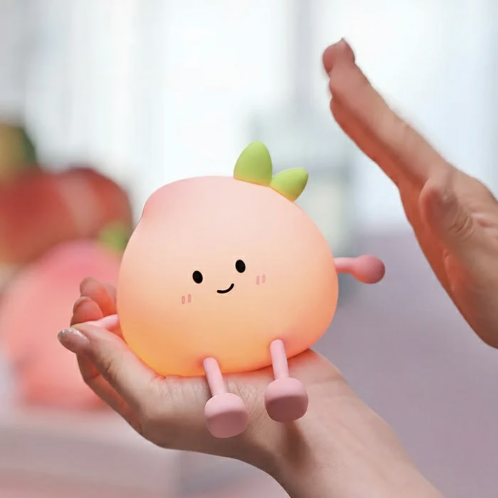 Cute peach-shaped night light held in a hand with a blurred background