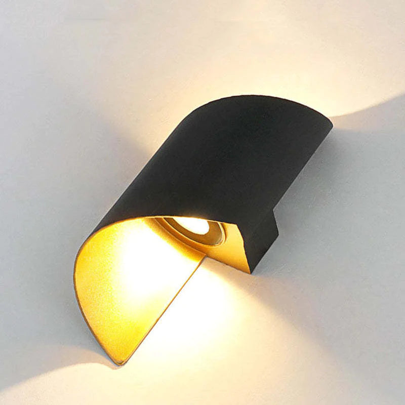 Modern wall-mounted light fixture with black and gold design on a white wall.