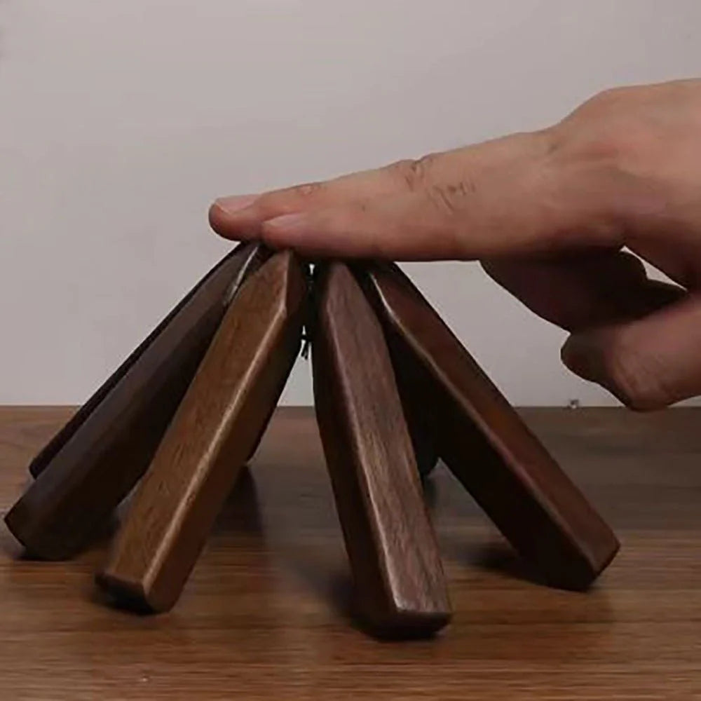 Wooden coasters stacked on a wooden surface with a hand lifting one coaster.