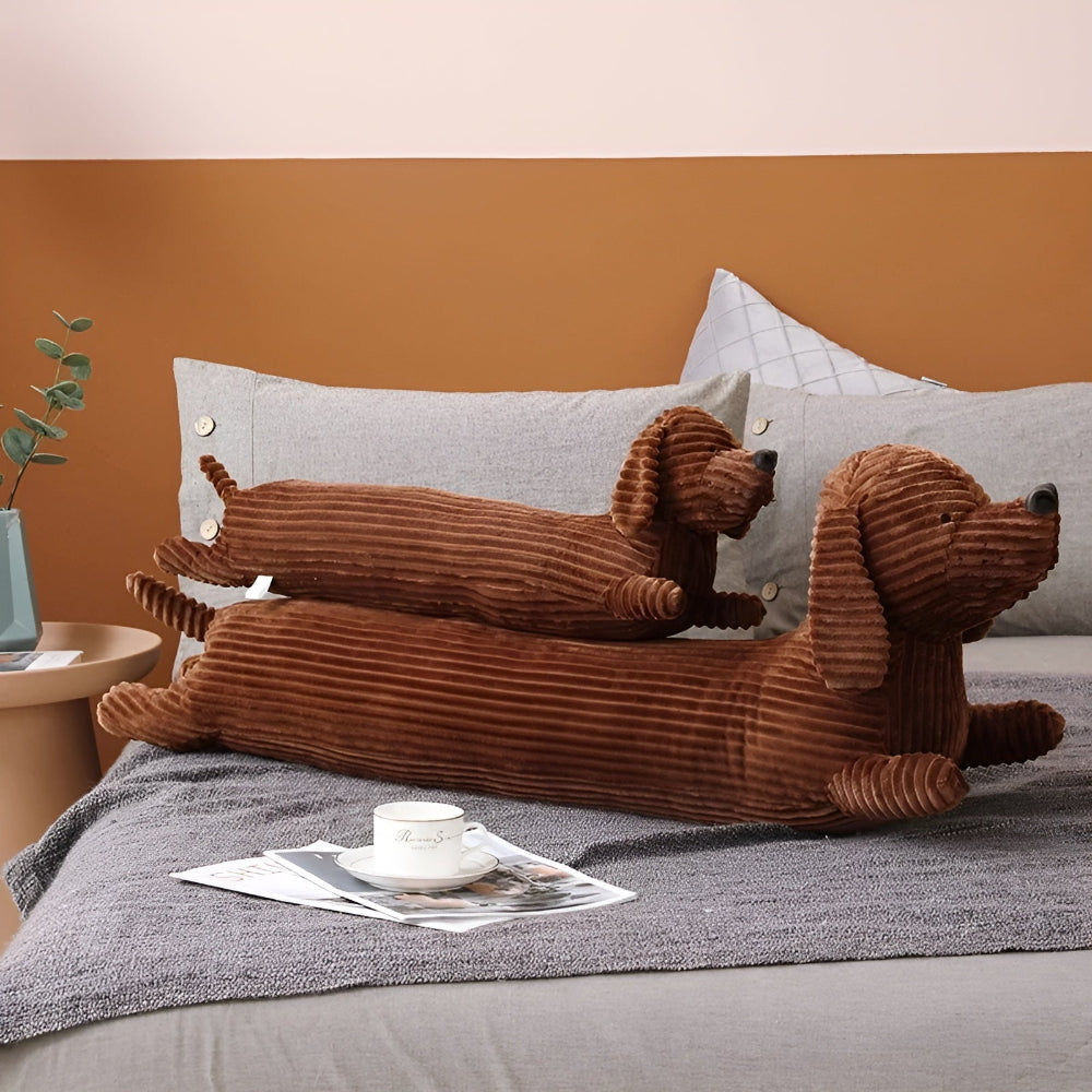 Two brown dog-shaped cushions on a sofa with a cup and magazine in the foreground.