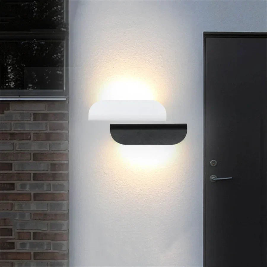 Modern wall-mounted light fixture on a white wall next to a door and brick wall.