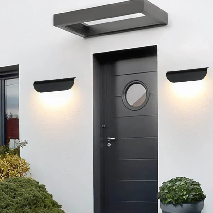 Modern black door with circular window and wall lights on a white wall.