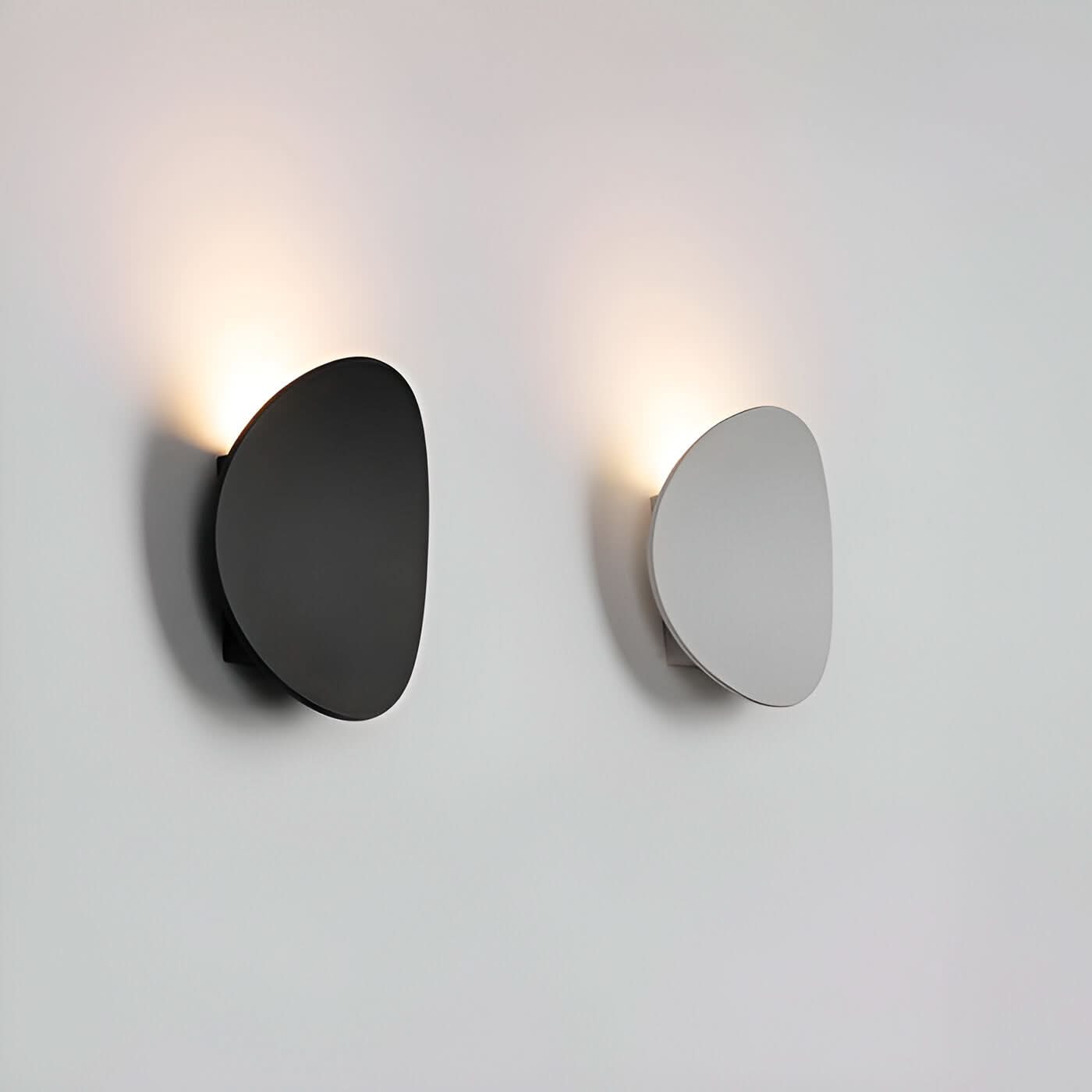 Two modern wall lights, one black and one silver, on a light gray background.
