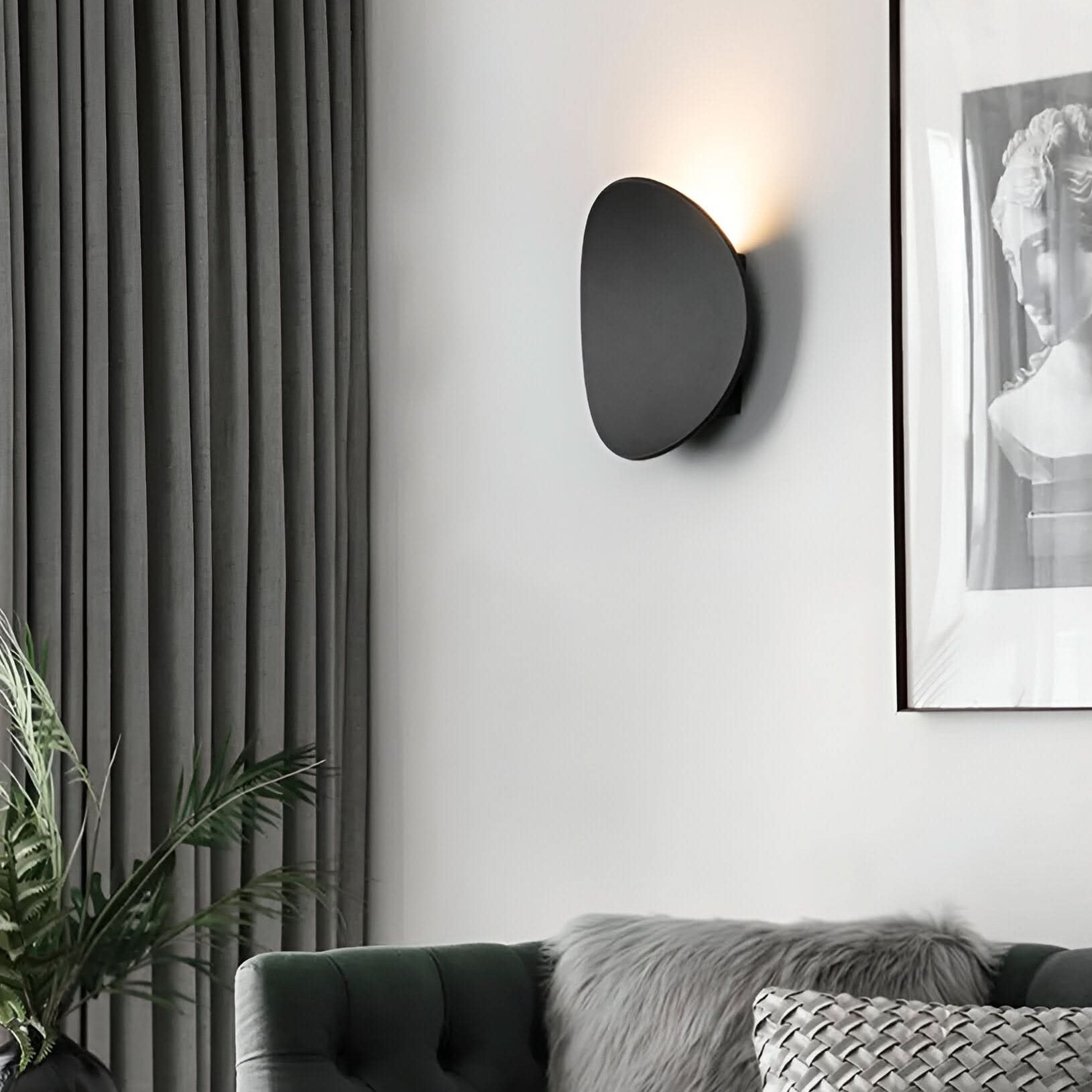 Modern living room with a wall-mounted light fixture, gray sofa, and framed artwork.