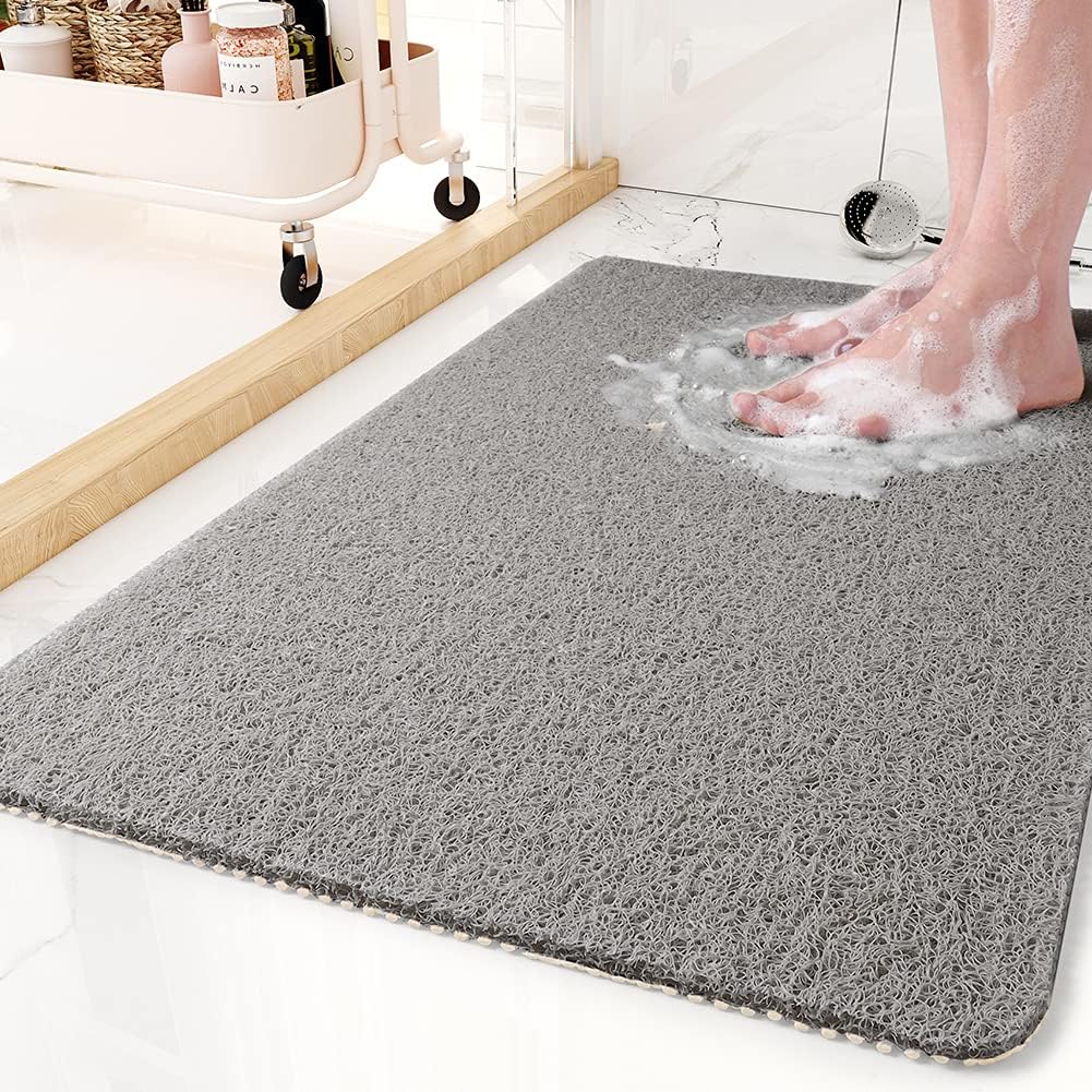 Gray bath mat with soapy water and feet on a bathroom floor.