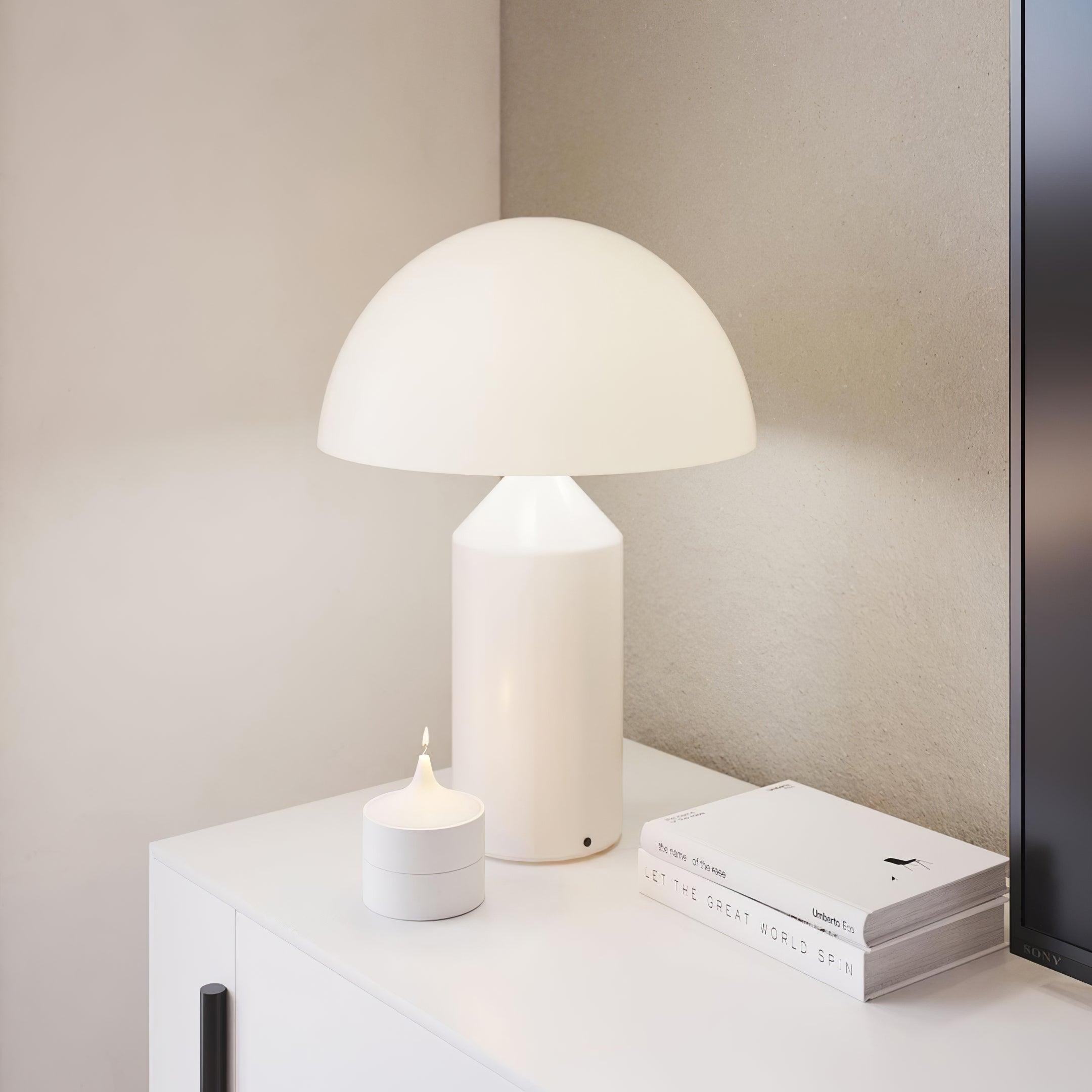 White table lamp on a surface with books and a candle in a minimalistic setting