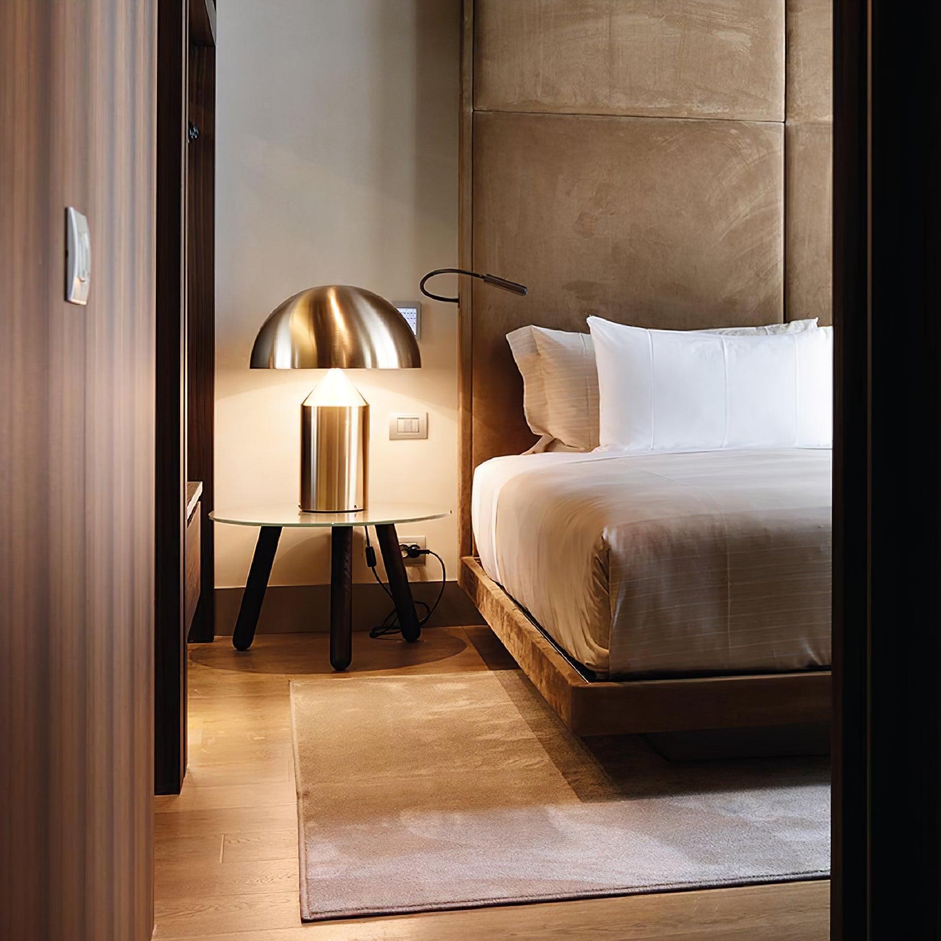 Modern bedroom with a bed, lamp, and side table.