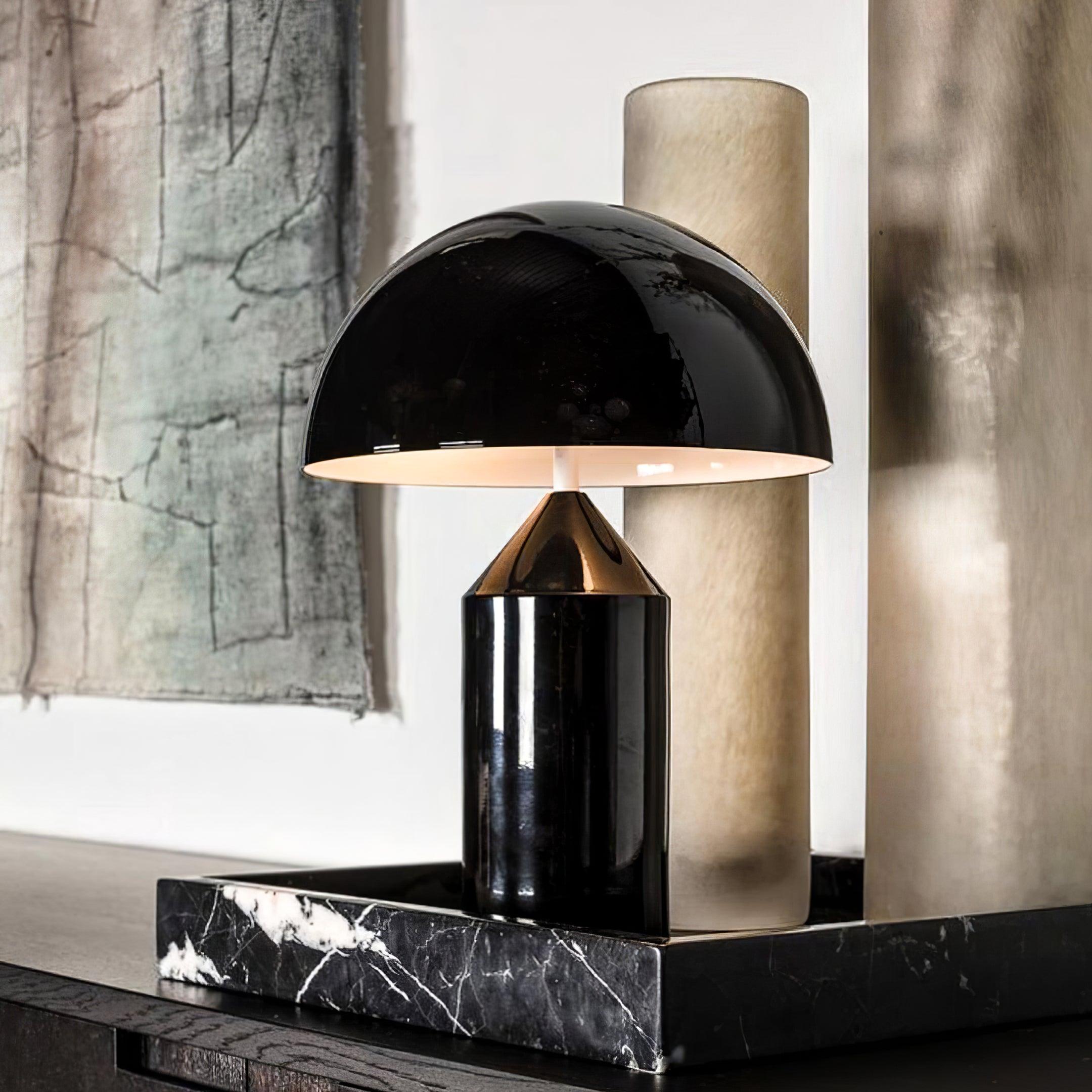Modern black table lamp on a marble surface with abstract art in the background