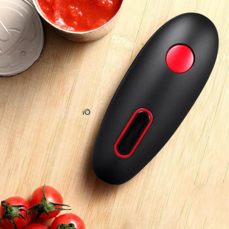 Black and red kitchen tool on a wooden surface with tomatoes and a container of red sauce.
