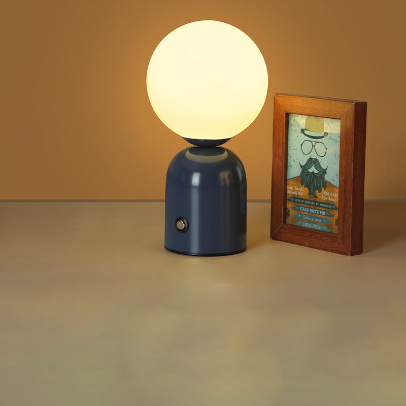 Small table lamp with a round bulb next to a framed picture on a beige surface.