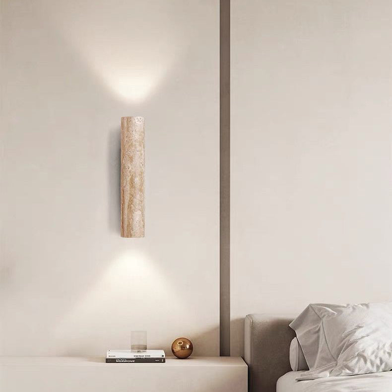 Modern wall sconce on a neutral wall with a bed in the background