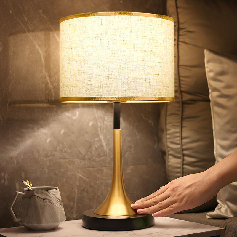 Decorative table lamp with a hand touching it on a marble surface.