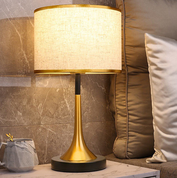 Gold table lamp on a marble surface with a couch and pillow in the background