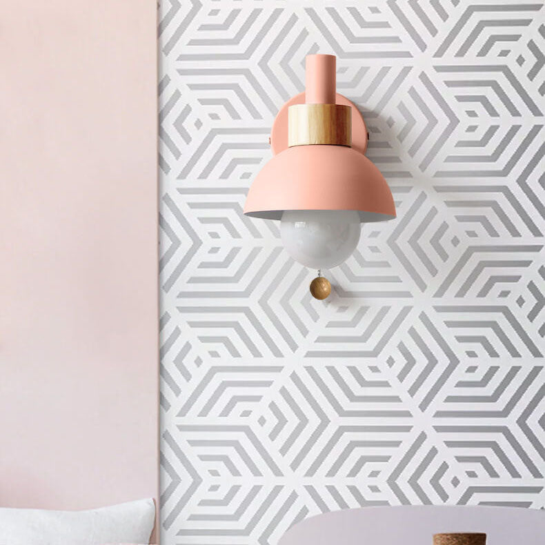 Pink wall sconce with gold accents on a geometric patterned wall.