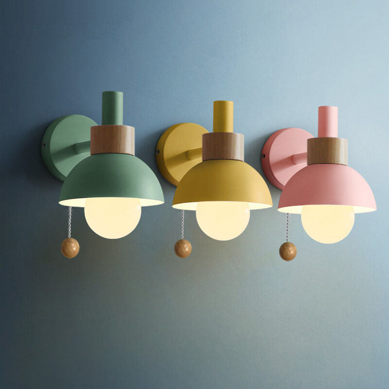 Three colorful wall lights with wooden accents on a blue wall.