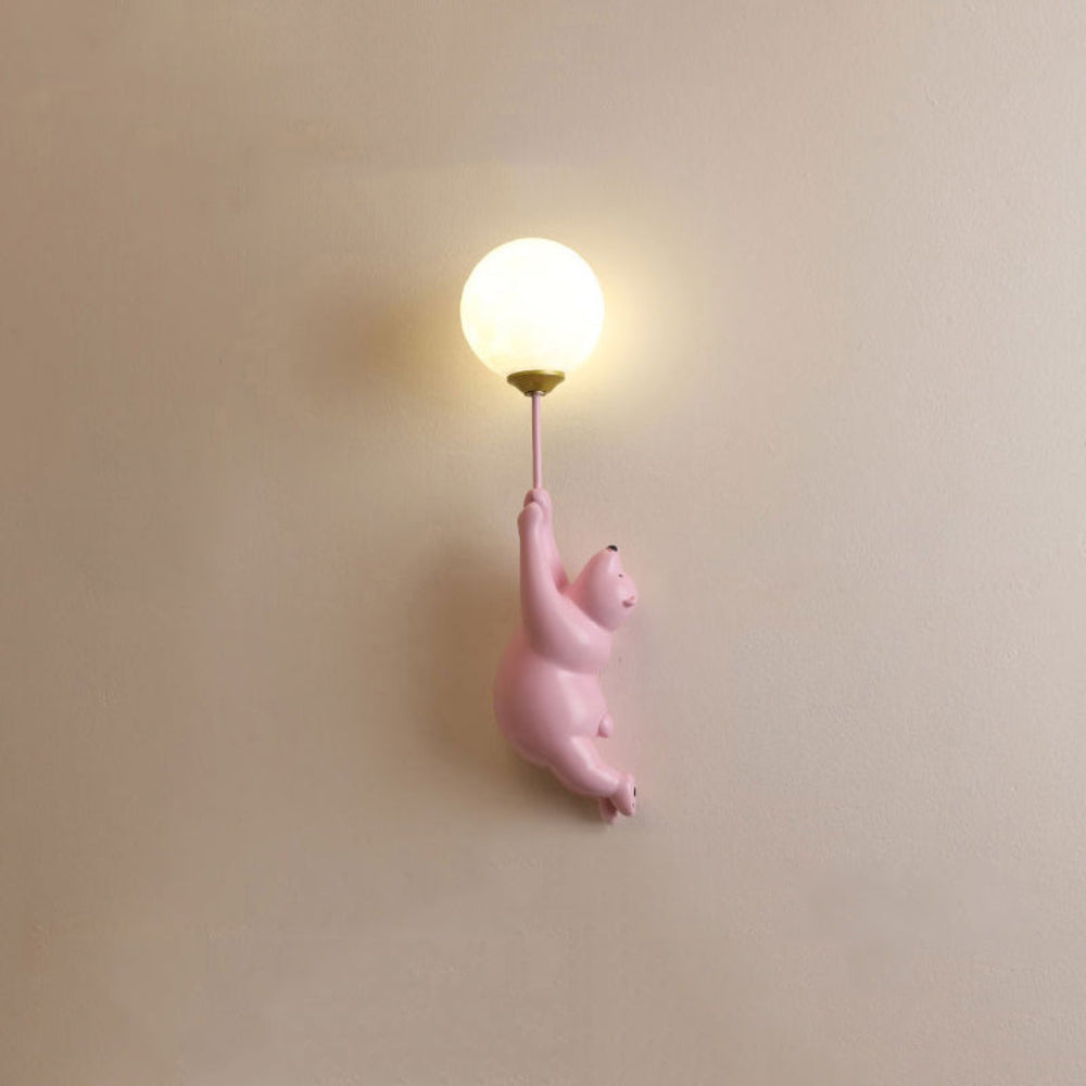 Wall-mounted light fixture with a pink bear design on a beige wall.