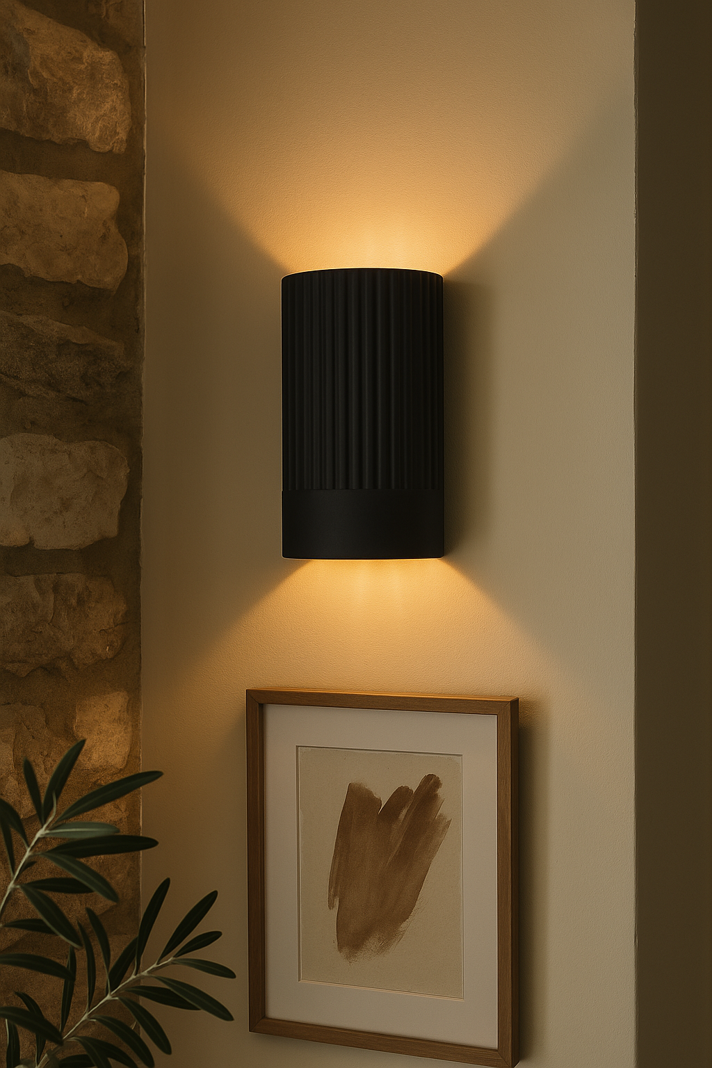 Black wall-mounted light fixture on a neutral wall with a framed picture and plant.