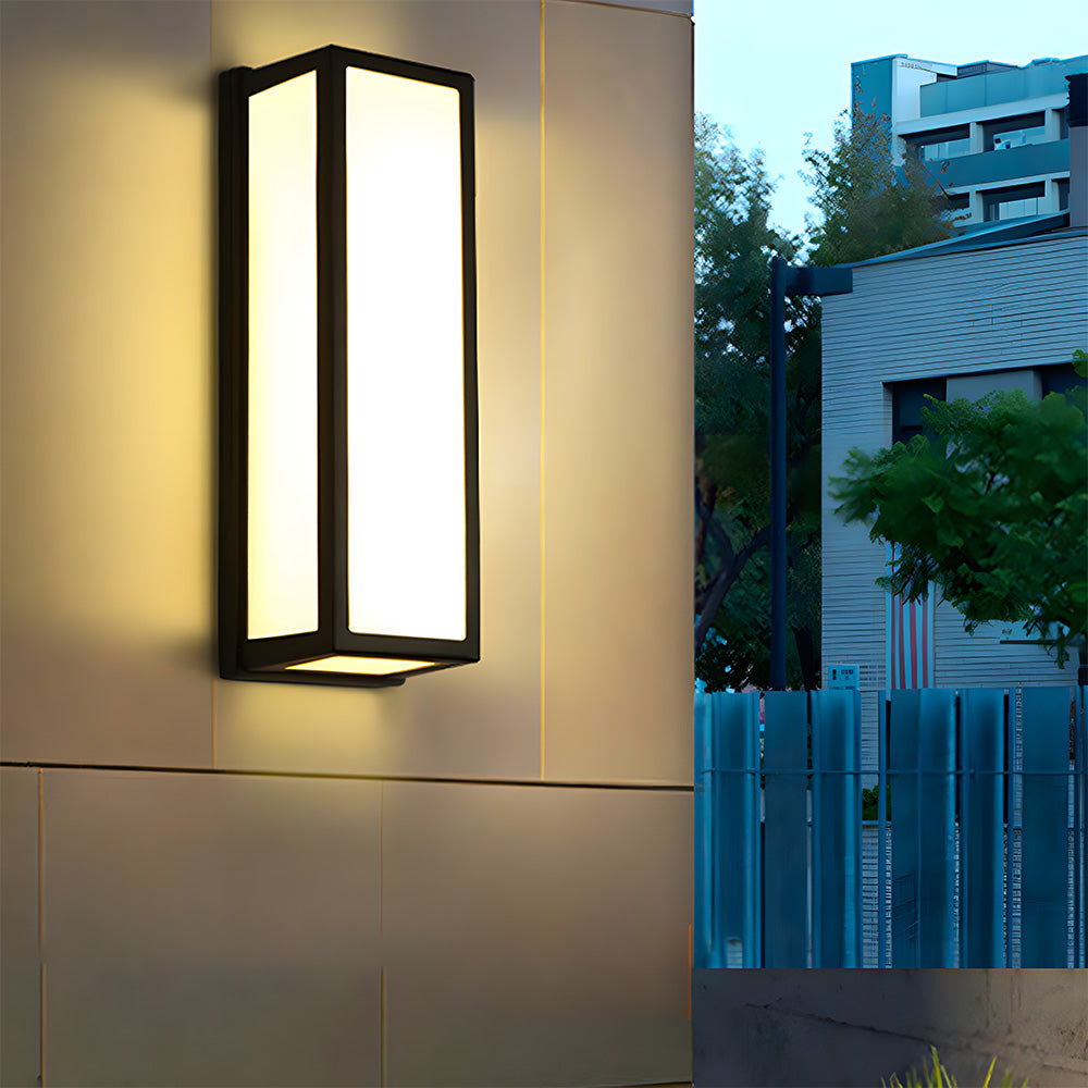 Modern outdoor wall light fixture on a building exterior with a residential area in the background.