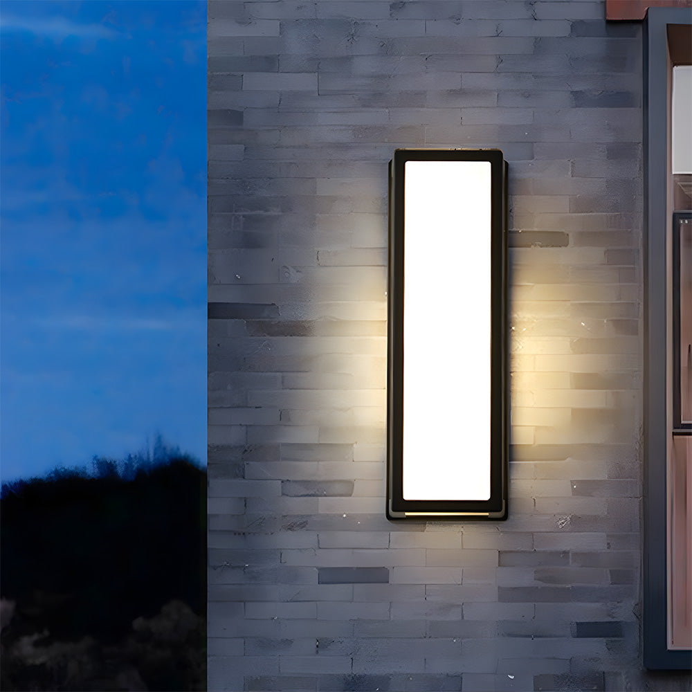 Rectangular wall-mounted light fixture on a brick wall at night.
