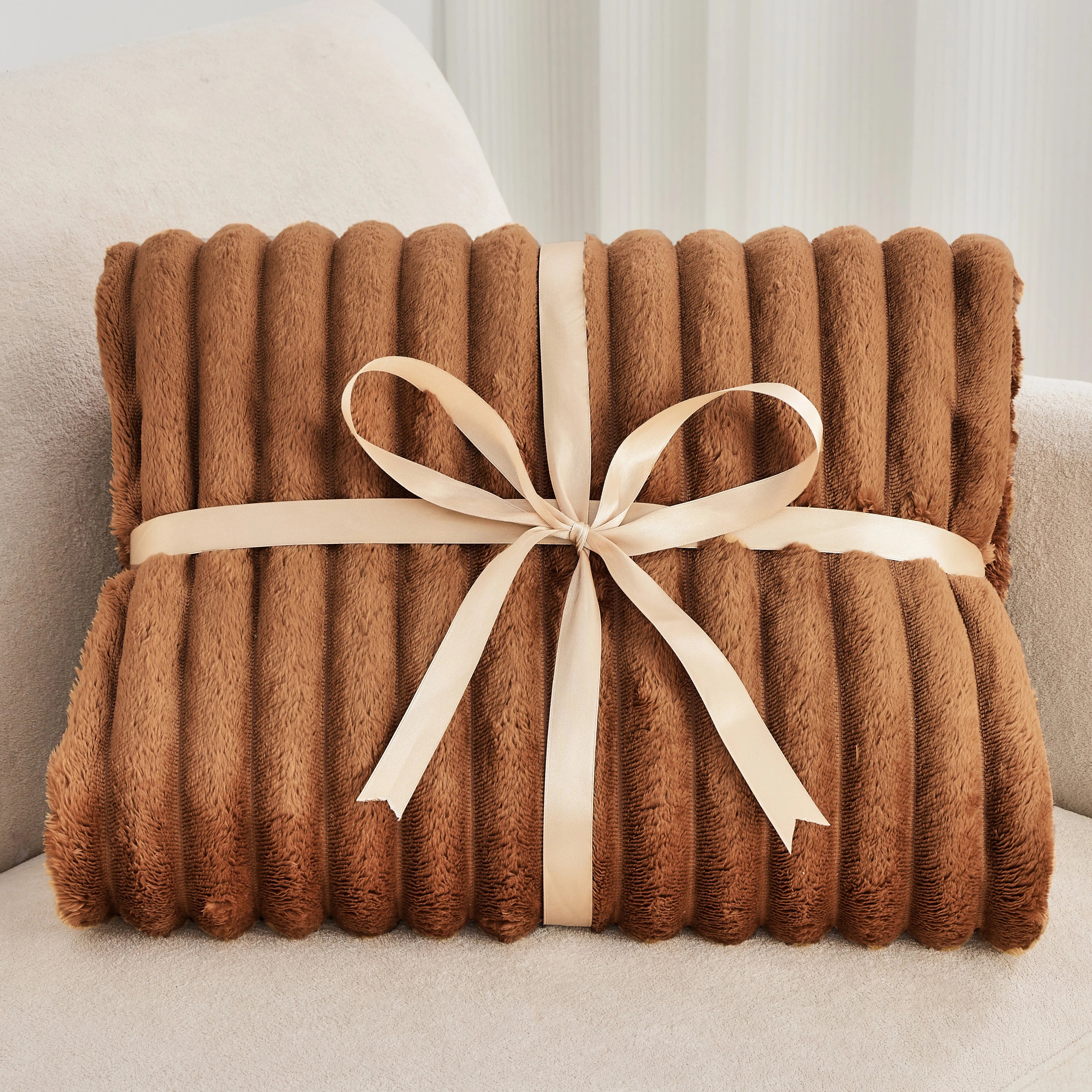Brown textured blanket with a beige ribbon on a light-colored surface