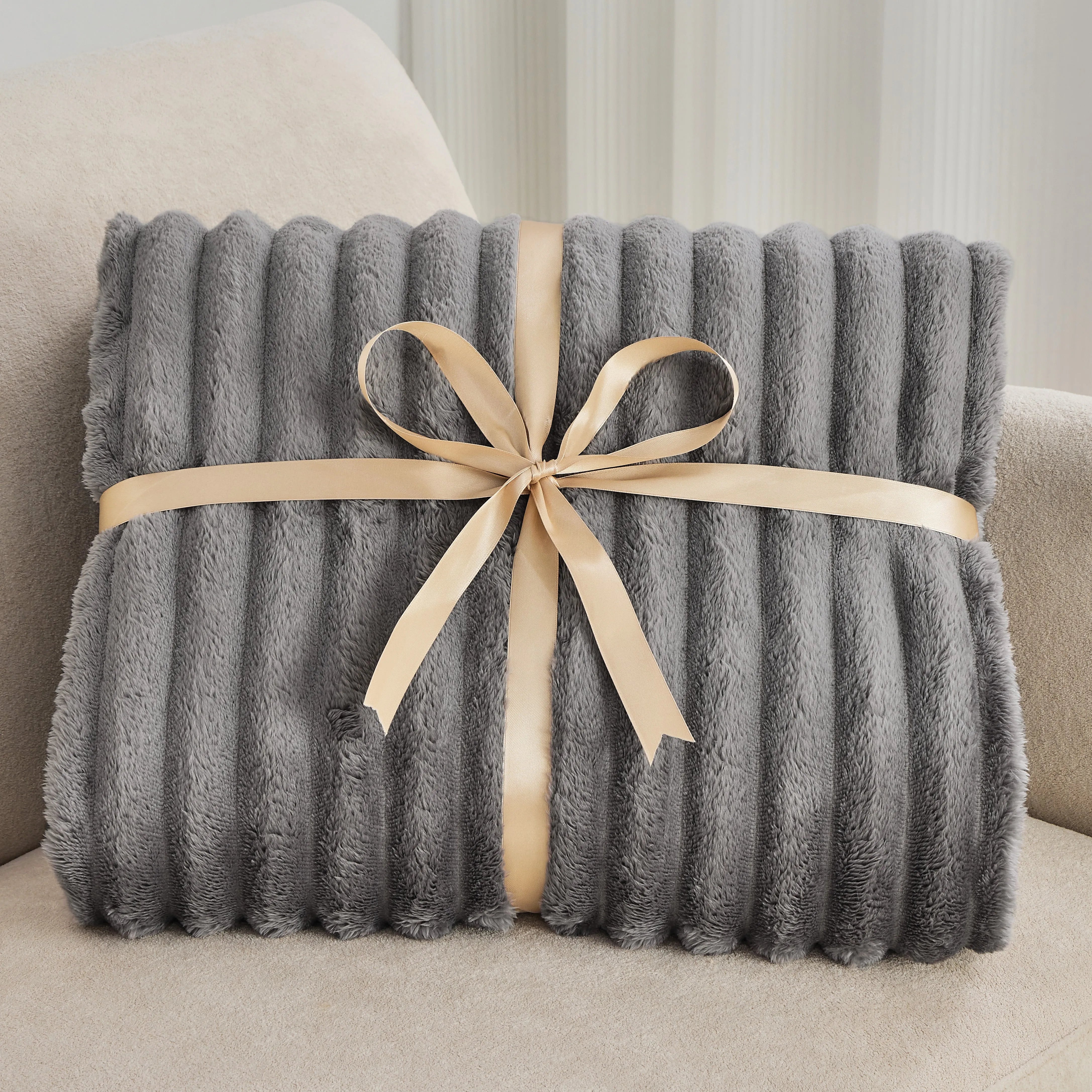 Gray blanket with a beige ribbon on a beige couch