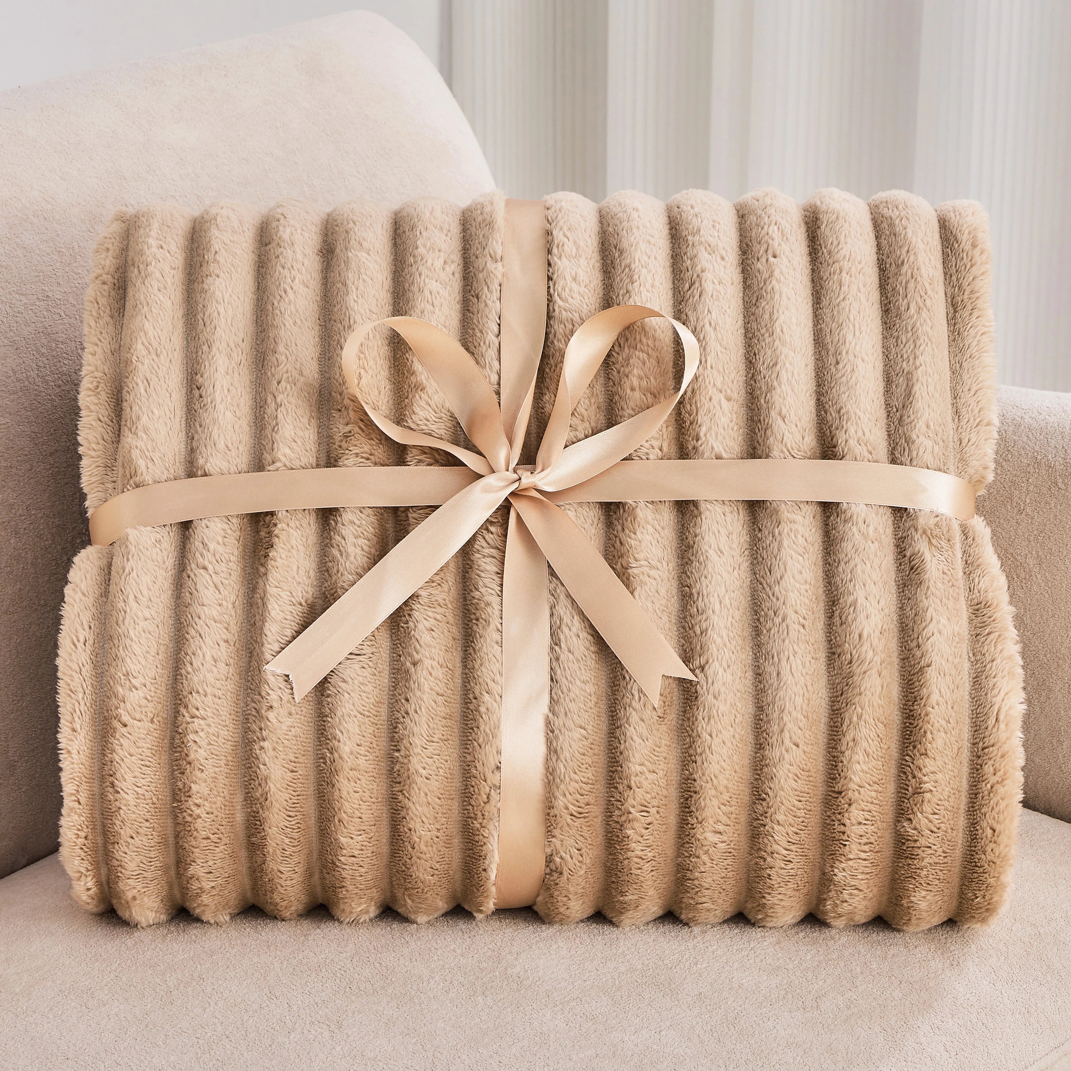 Beige blanket with a ribbon on a light-colored couch