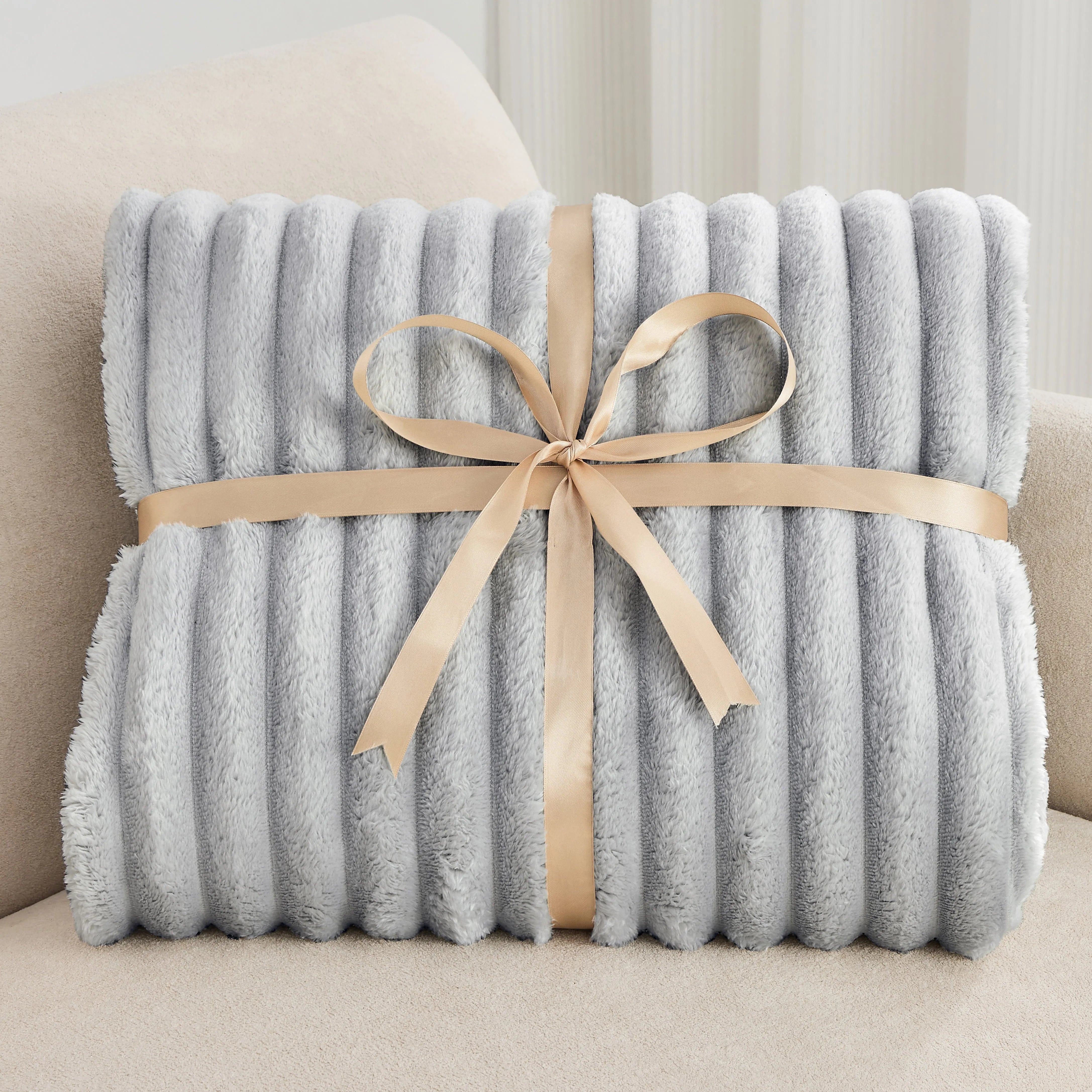Gray blanket with a beige ribbon on a light-colored couch