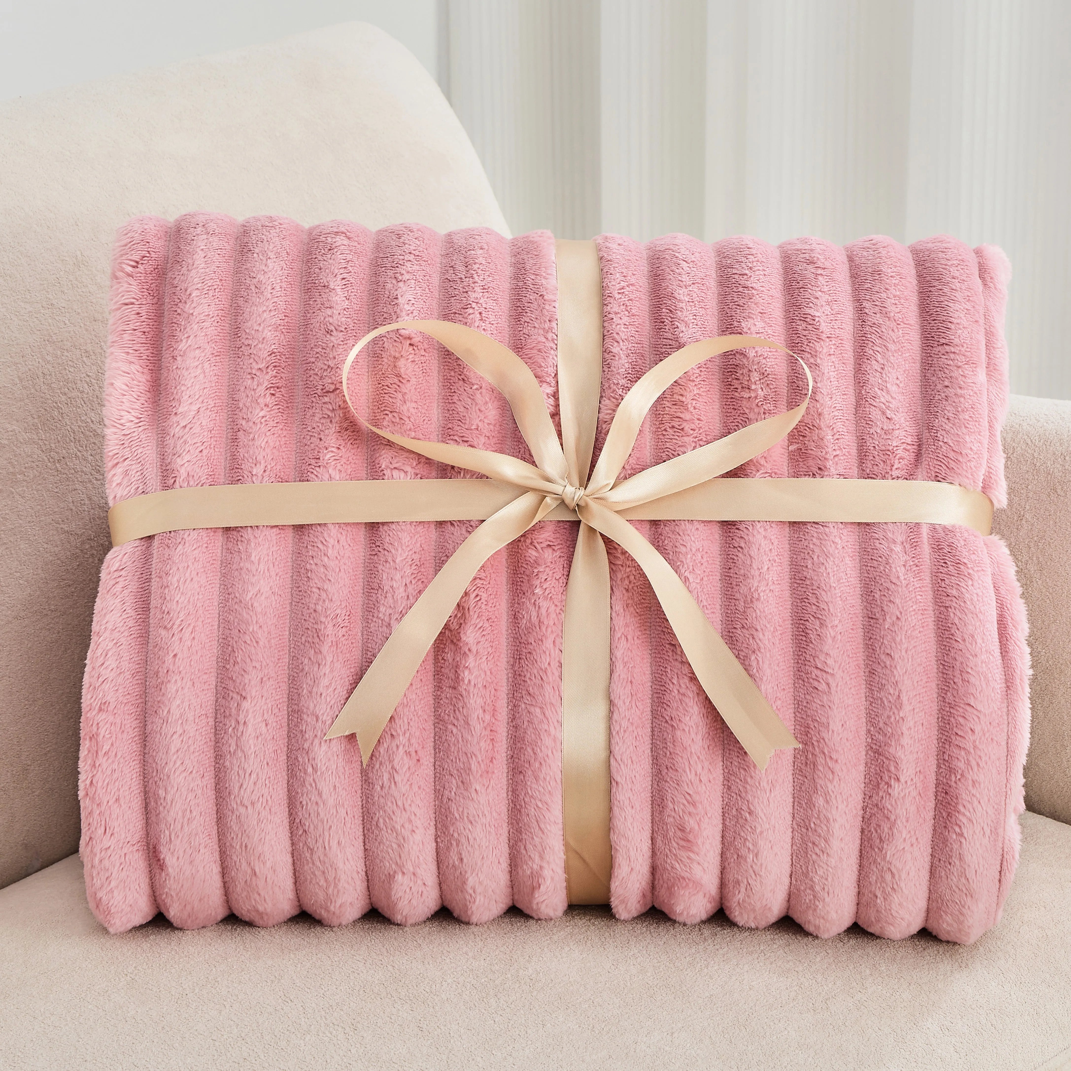 Pink blanket with a beige ribbon on a light-colored couch