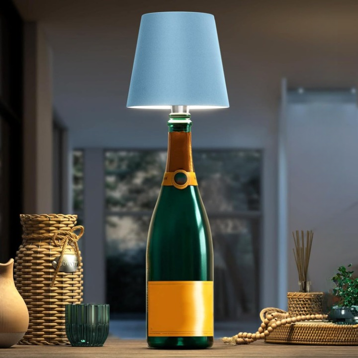 Bottle-shaped lamp with blue shade on a table with decorative items.
