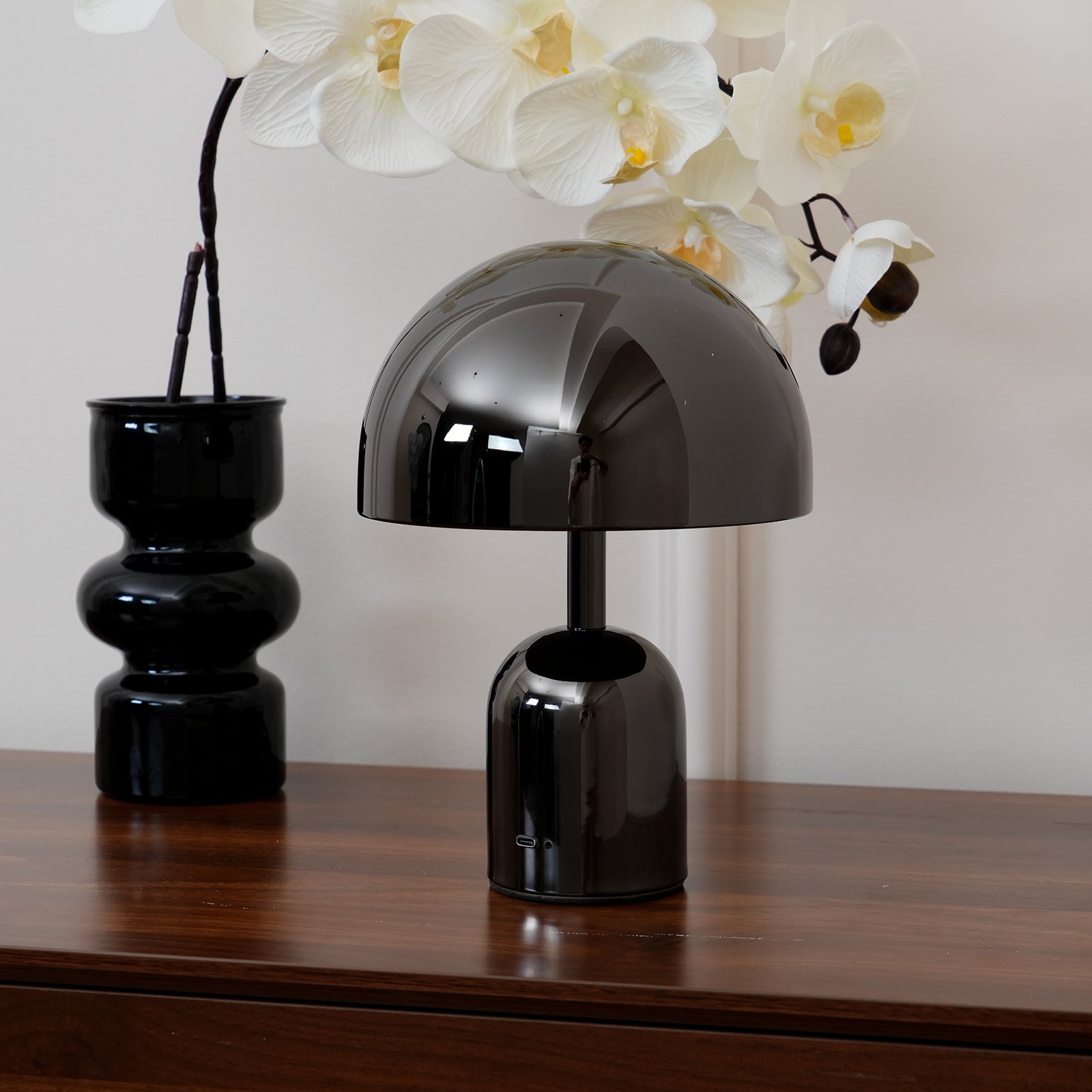 Black table lamp on a wooden surface with white flowers in the background